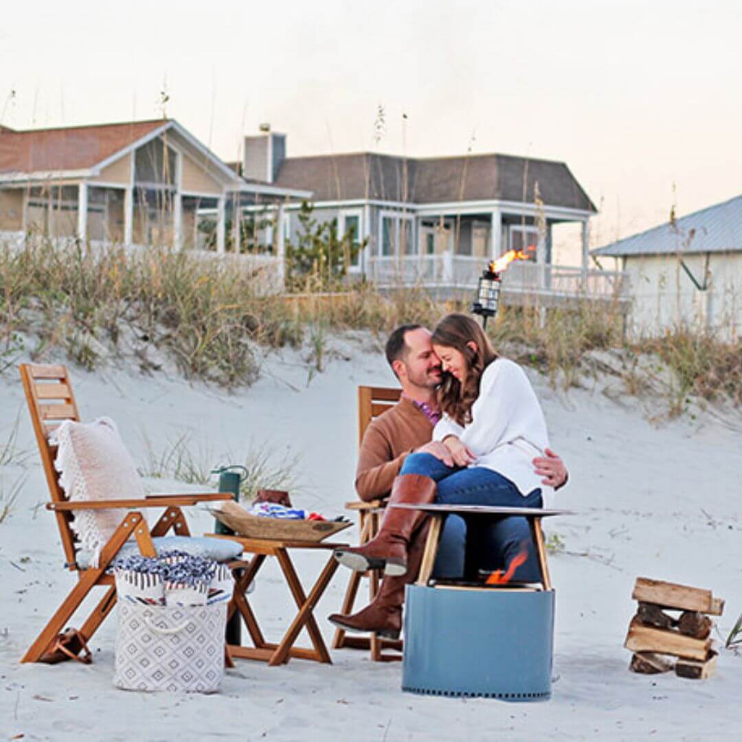 a man and woman sitting at a table with chairs and a fire