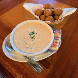 A bowl of She Crab soup with a package of saltines and a side of hush puppies from Lee's Kitchen